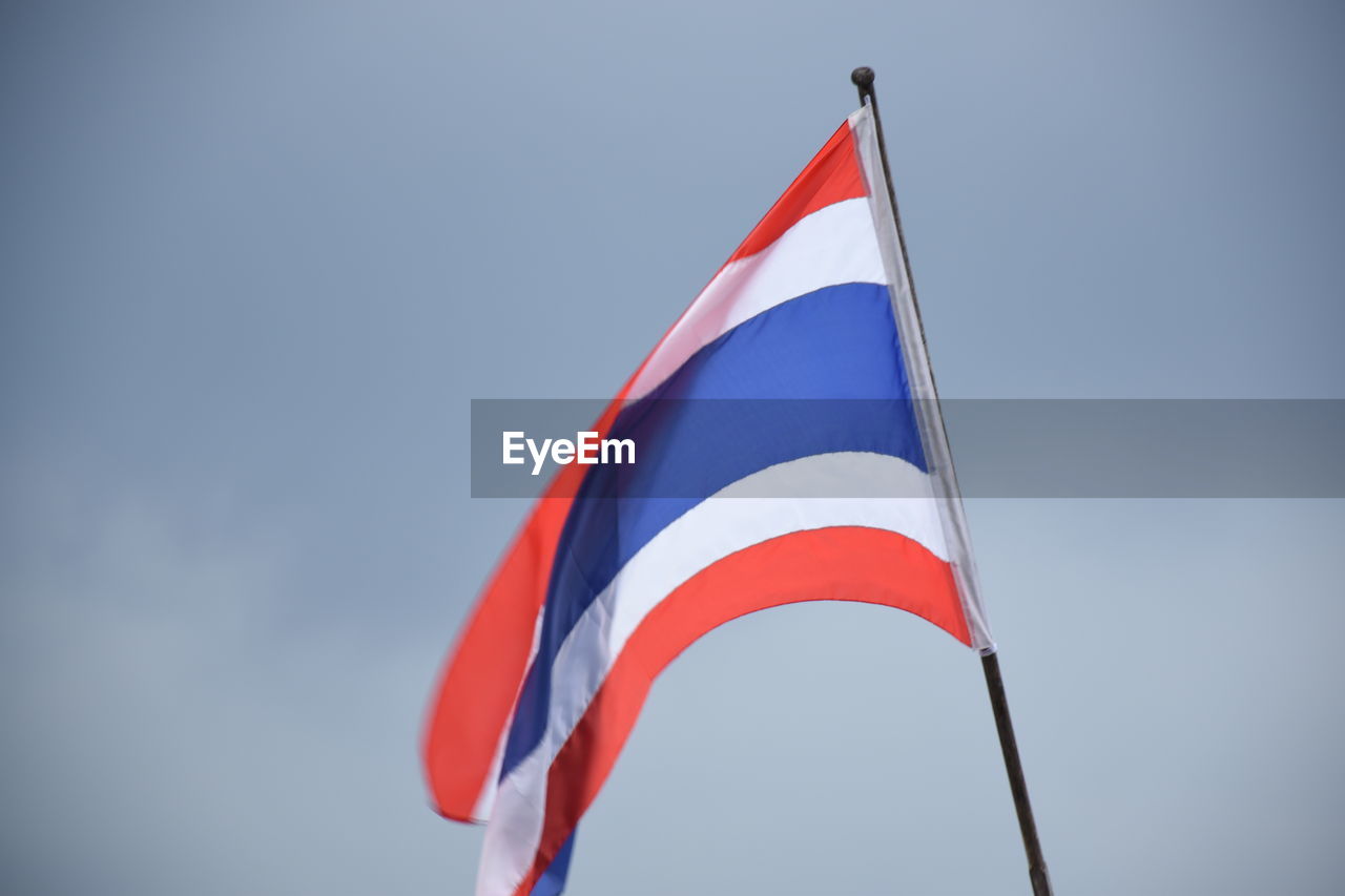 Low angle view of thai flag against blue sky