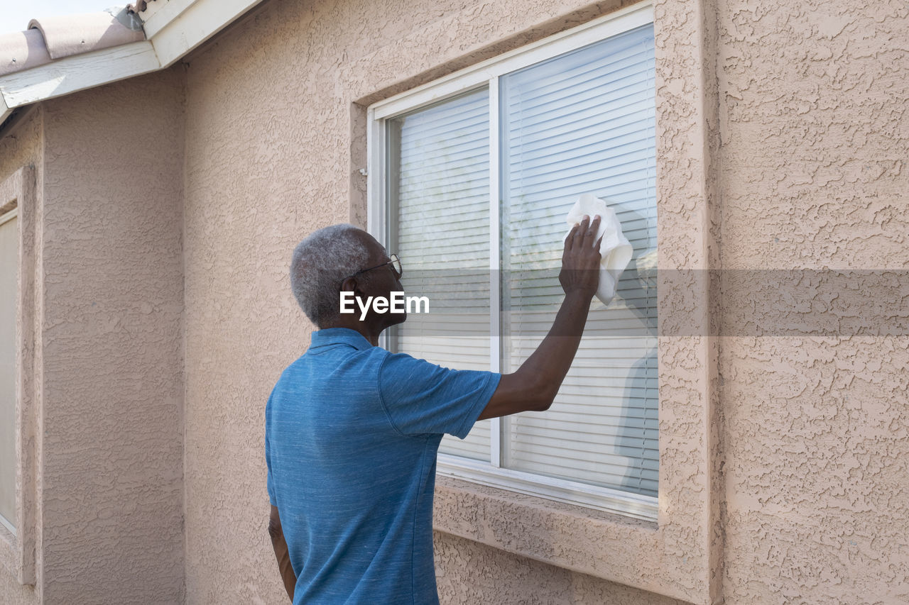 Man cleaning window of house