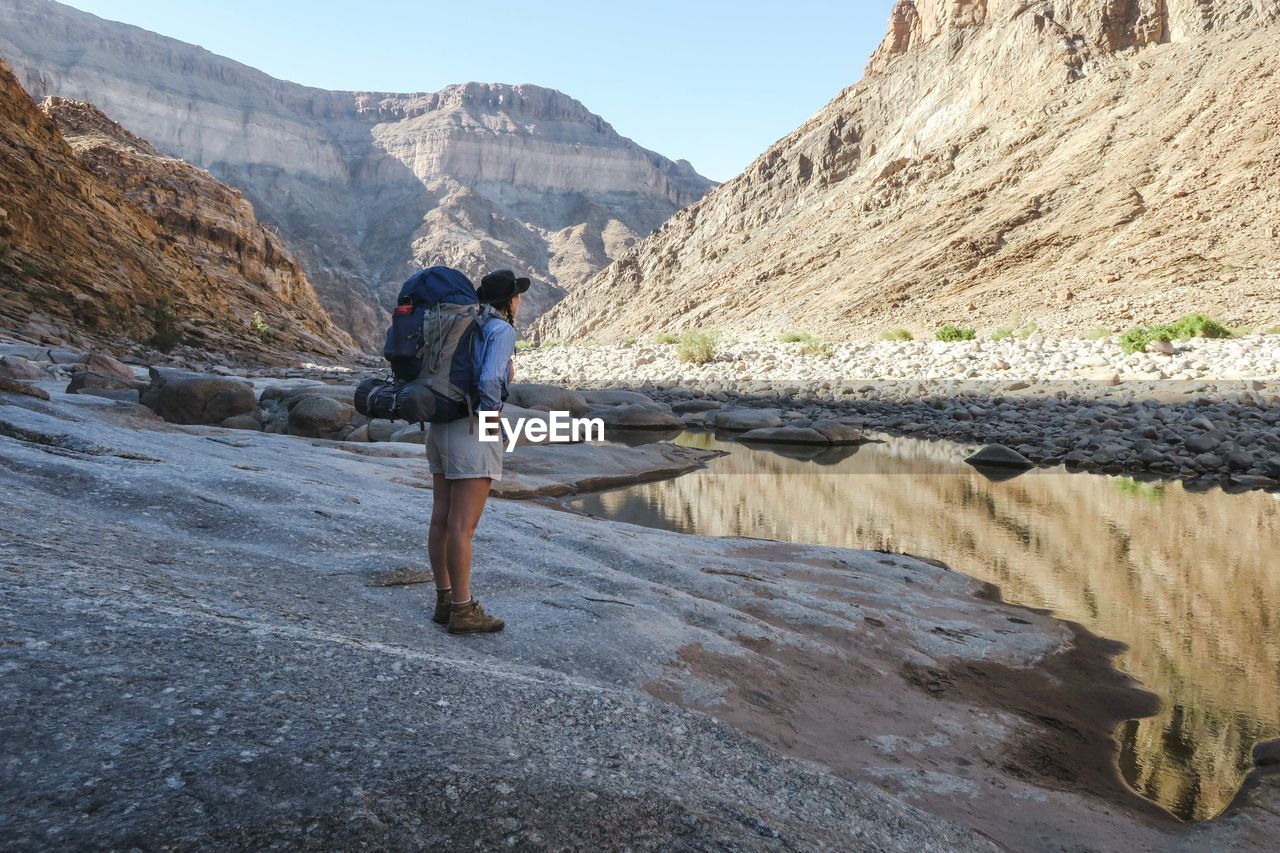 Woman standing by lake against mountain