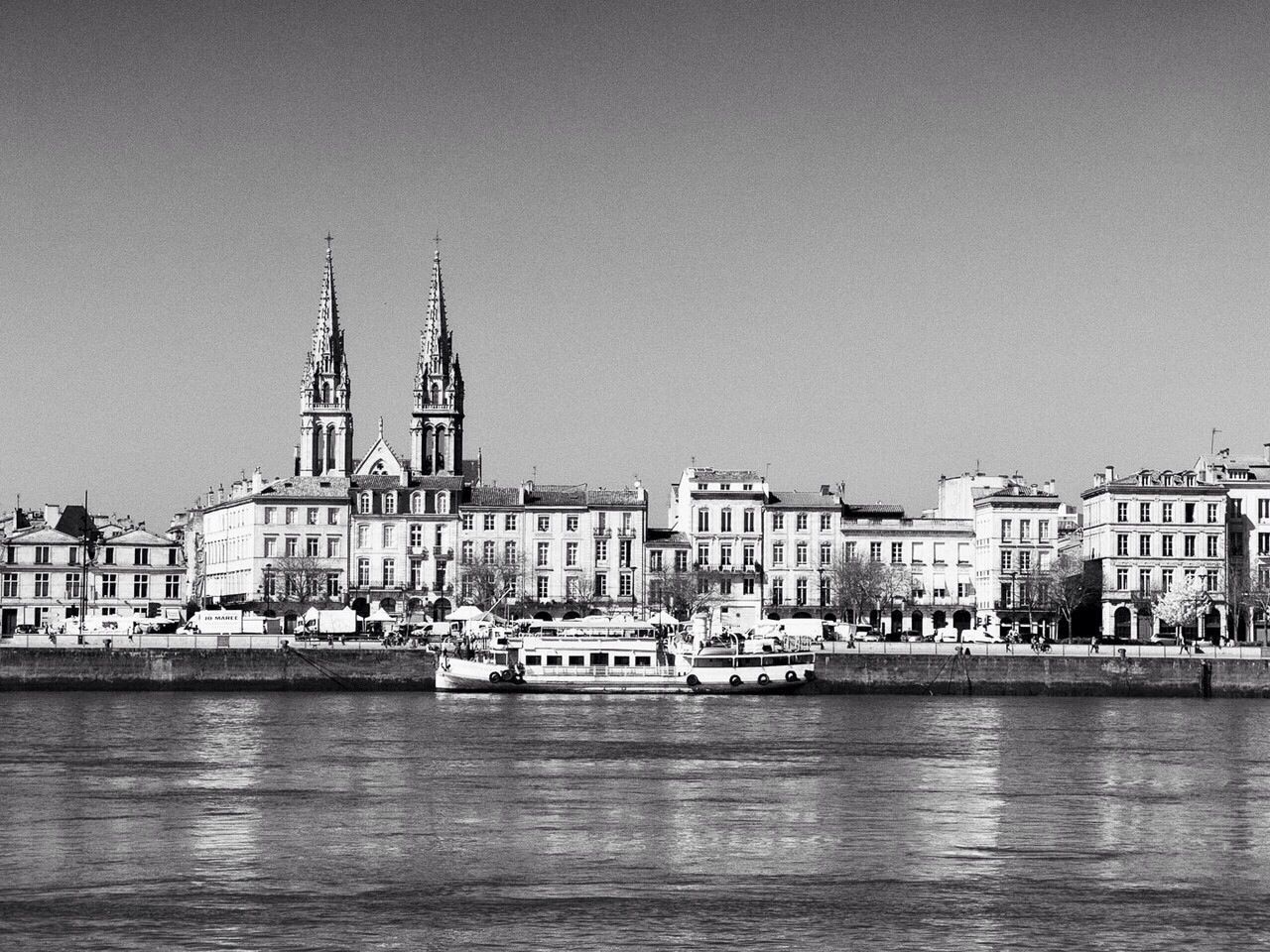 Ferry moored on river by church in town against clear sky