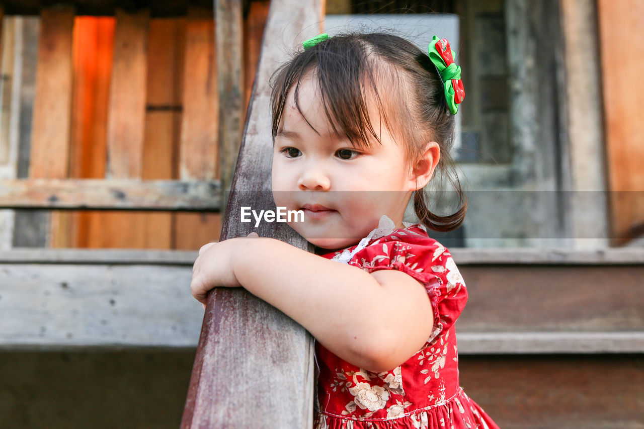 Portrait of cute girl at wooden stairs looking away