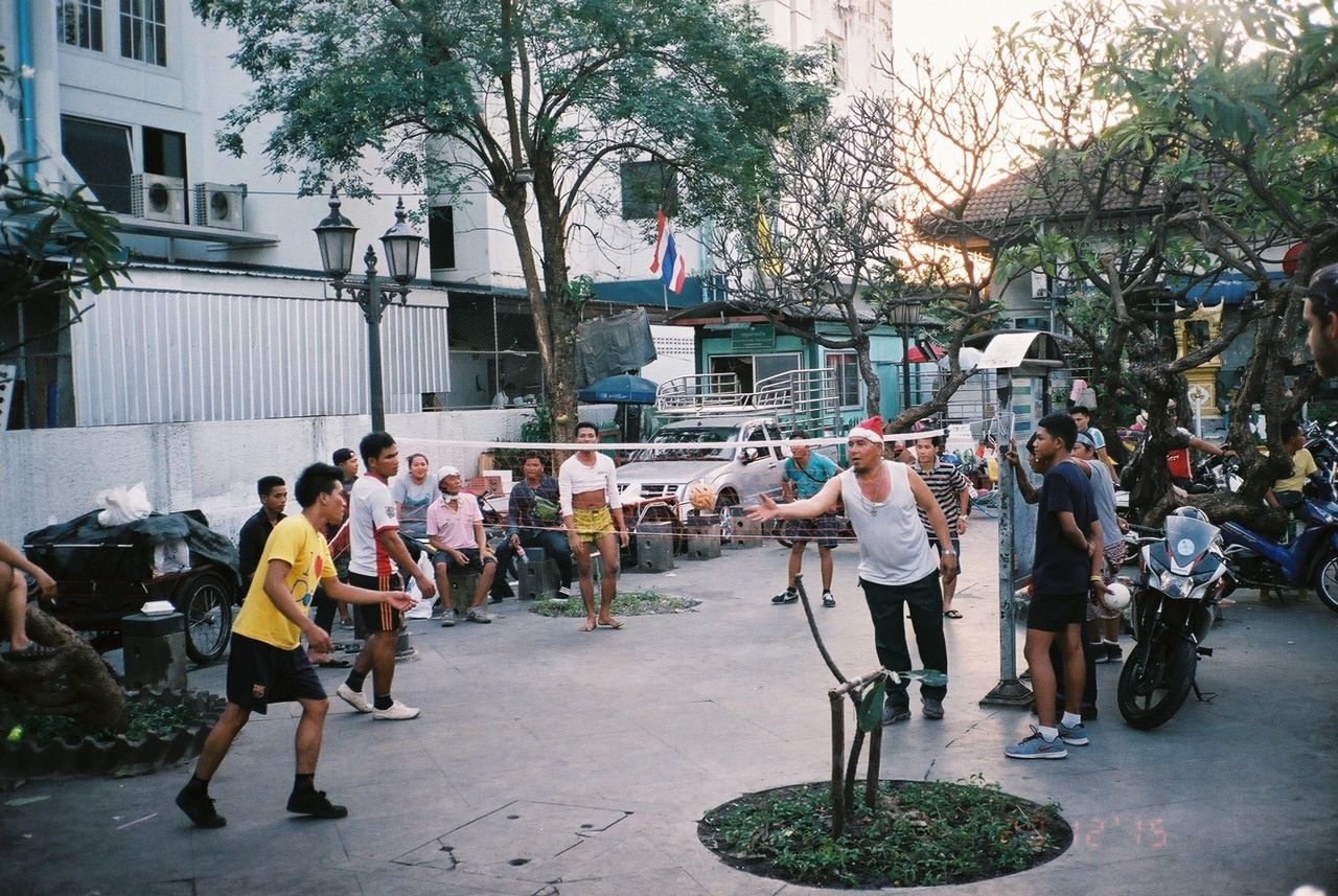 Men playing volleyball on street against buildings