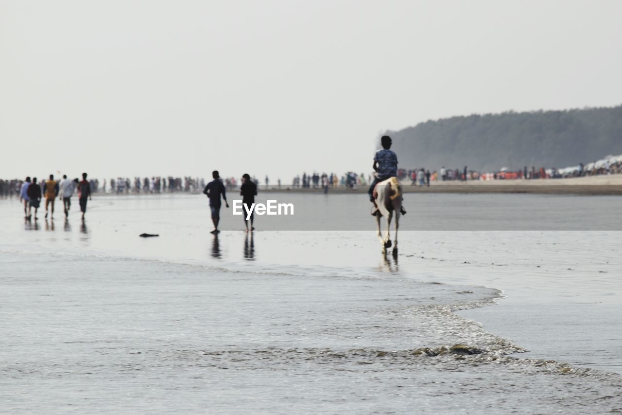 People at beach against clear sky