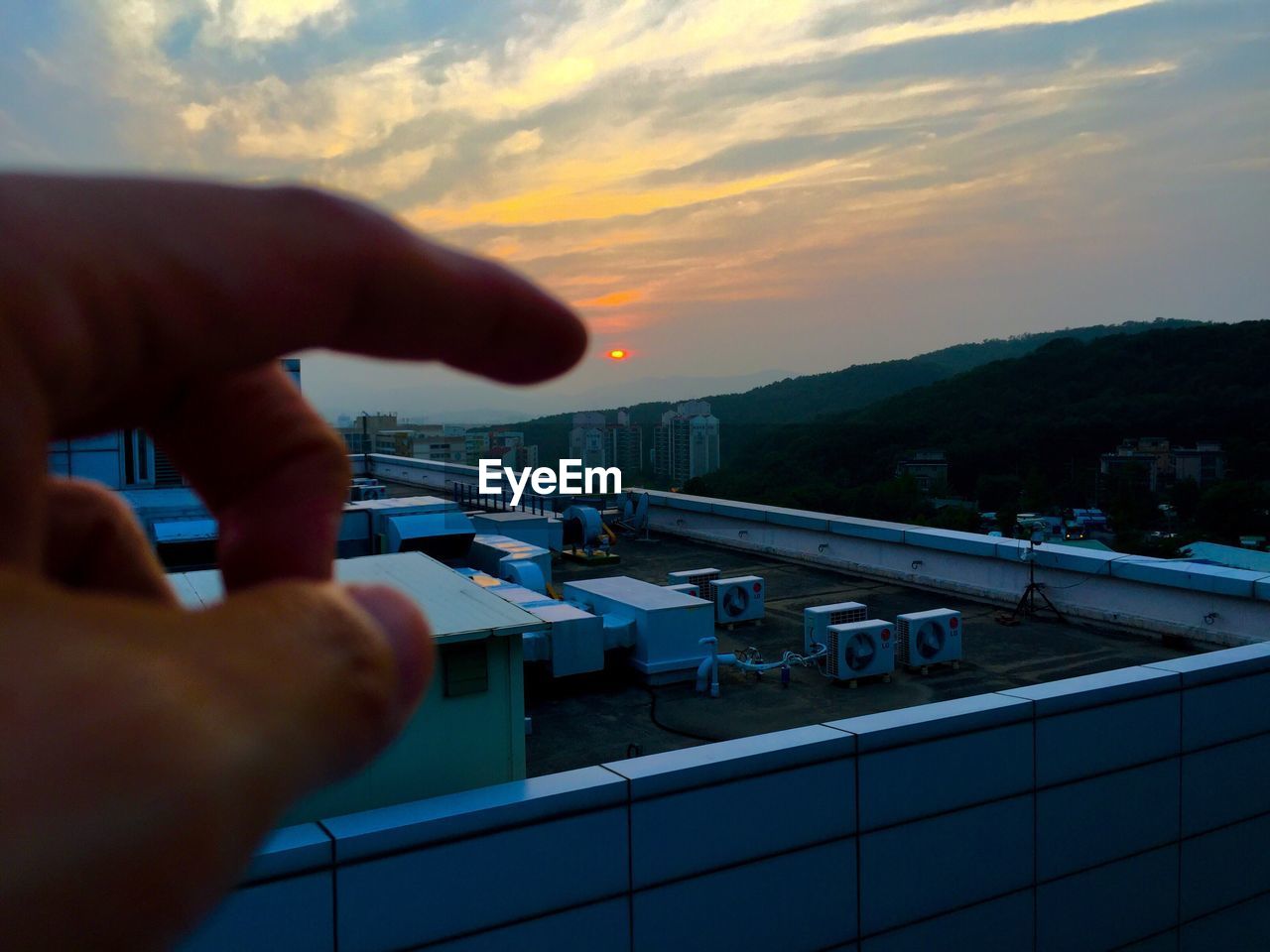 CLOSE-UP OF PERSON HAND HOLDING SEA AGAINST SKY