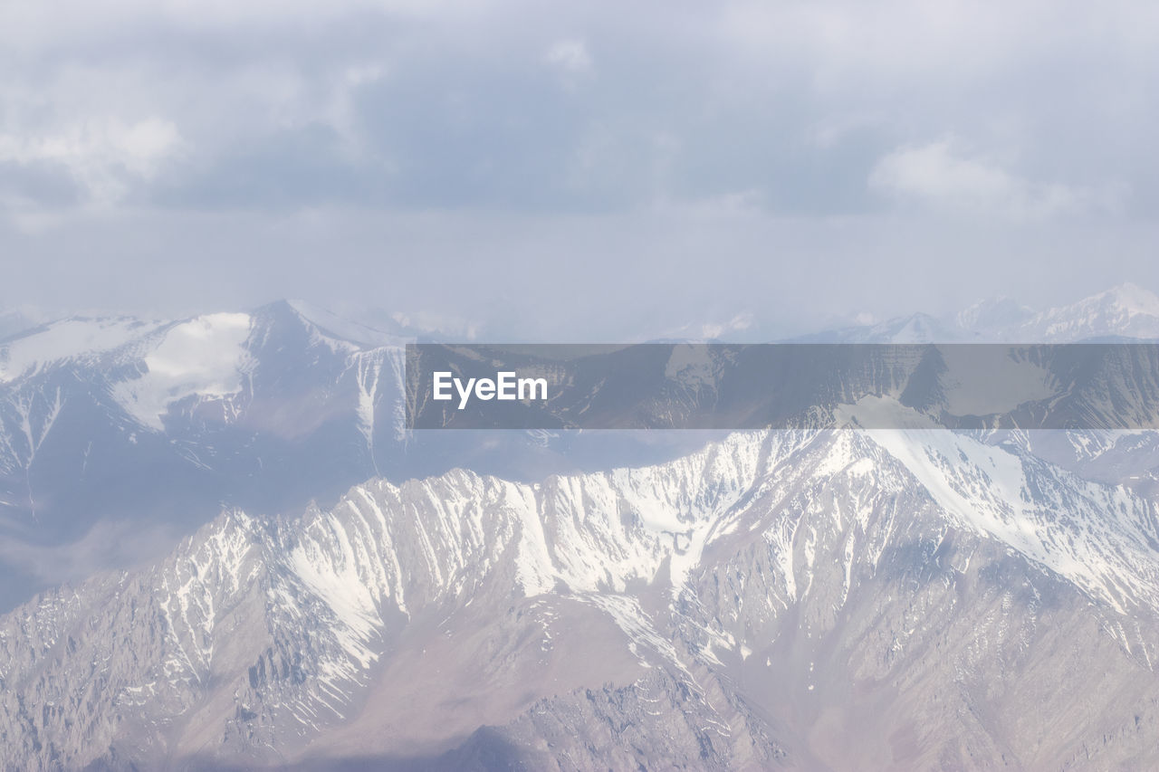 AERIAL VIEW OF SNOWCAPPED MOUNTAINS AGAINST SKY DURING WINTER