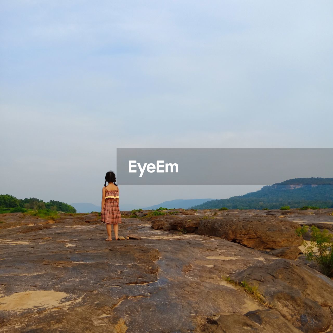 REAR VIEW OF WOMAN STANDING ON MOUNTAIN