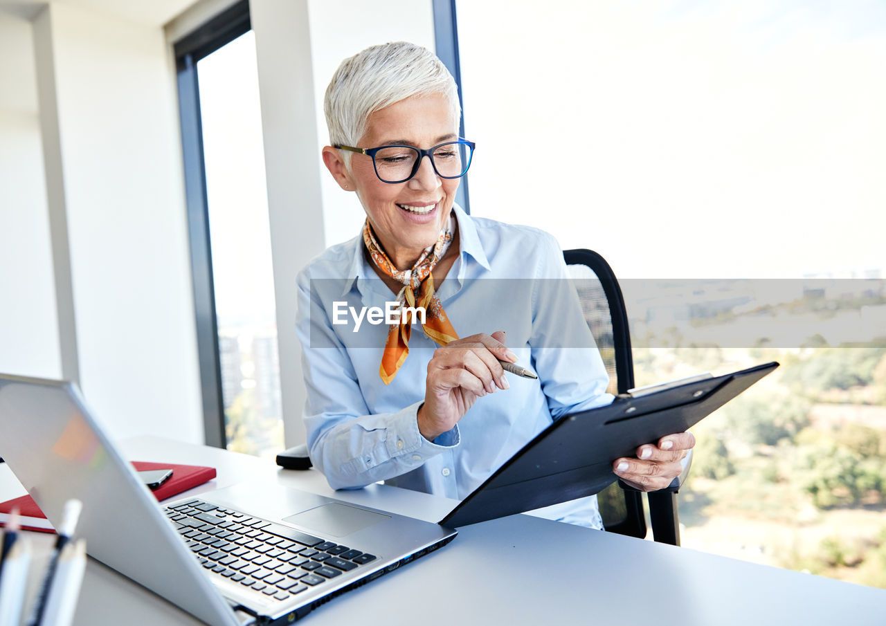 Smiling businesswoman working while sitting at table