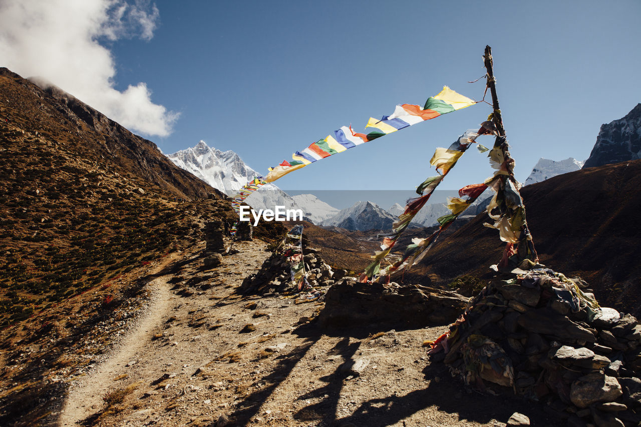 Colorful prayer flags hanging on mountain against blue sky during sunny day