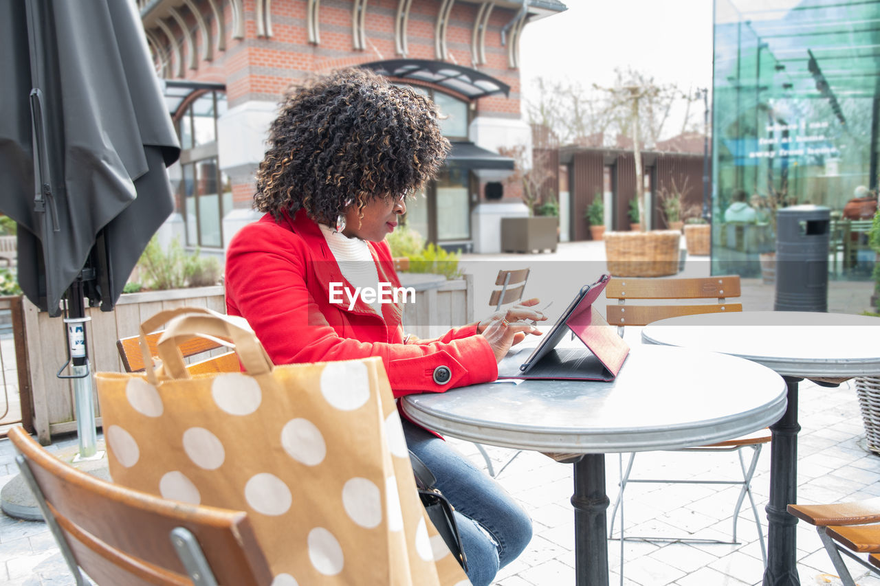 A young african american woman in a red coat cheking bill after shopping