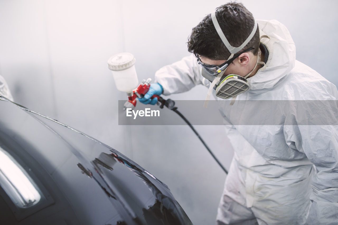 Auto painter painting a car inside a paint booth