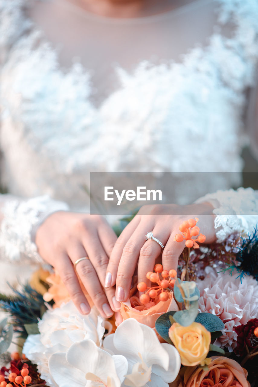 Midsection of bride with flowering plants