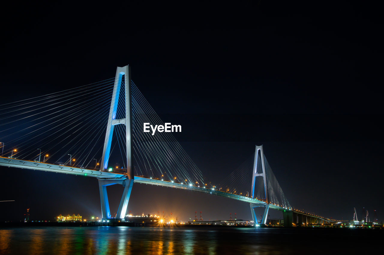 Illuminated suspension bridge over river at night