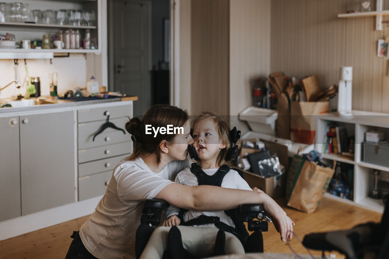 Mother taking care of disabled child in wheelchair at home