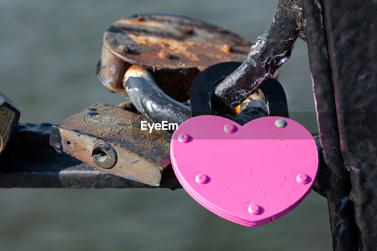 Pink heart-shaped padlock attached to bridge, close up