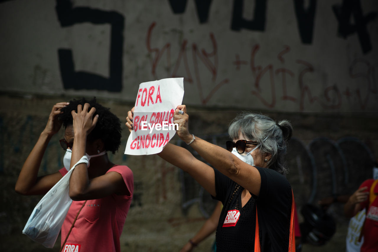 REAR VIEW OF PEOPLE WITH TEXT STANDING AGAINST THE BACKGROUND