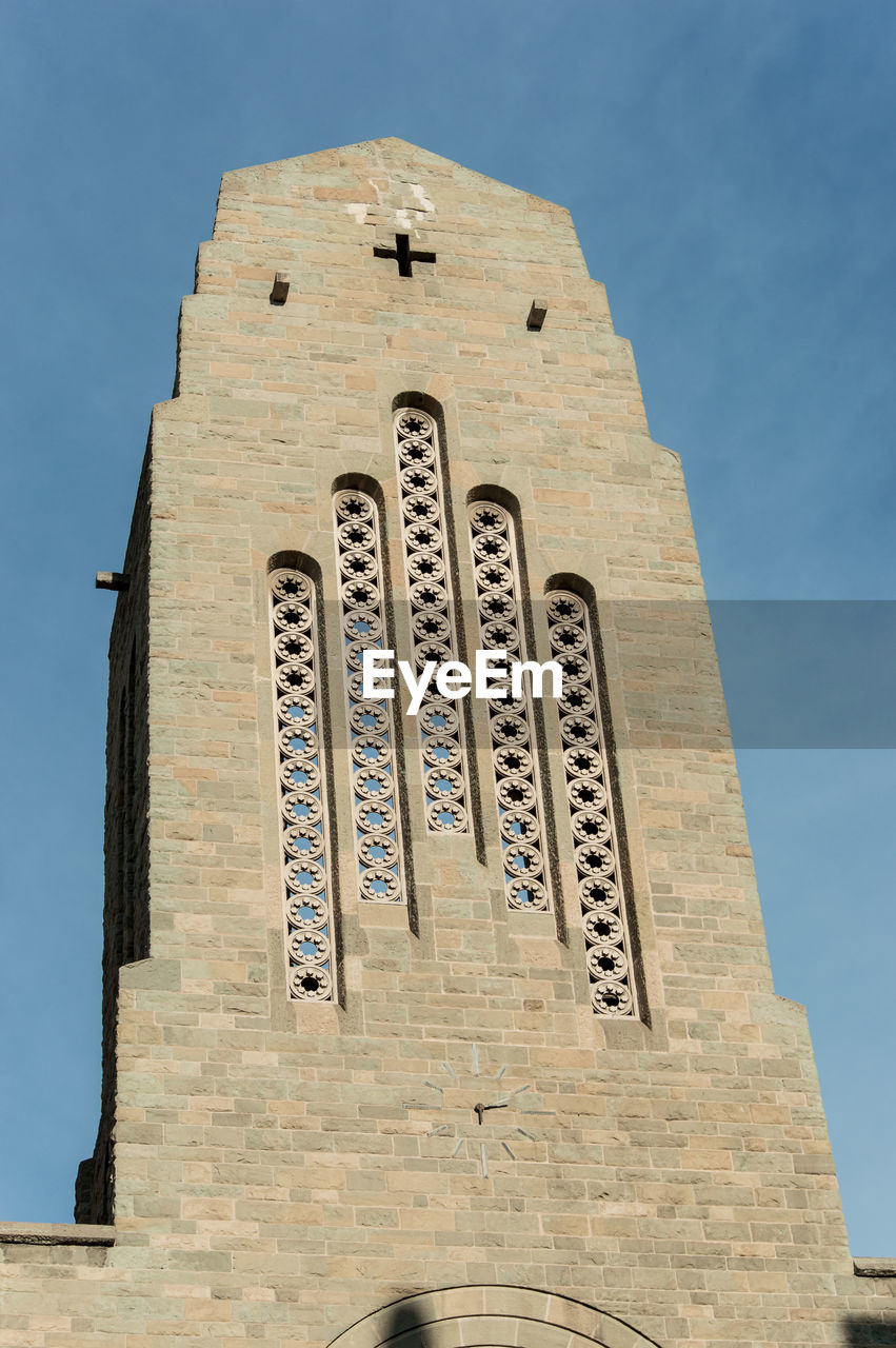 Low angle view of cross on building against sky