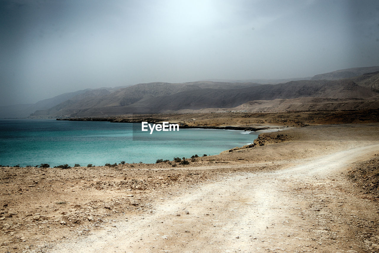SCENIC VIEW OF SEA BY MOUNTAINS AGAINST SKY
