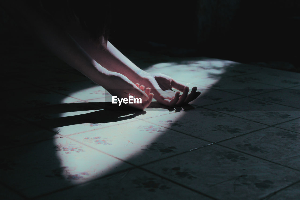 Cropped hands of woman on tiled floor