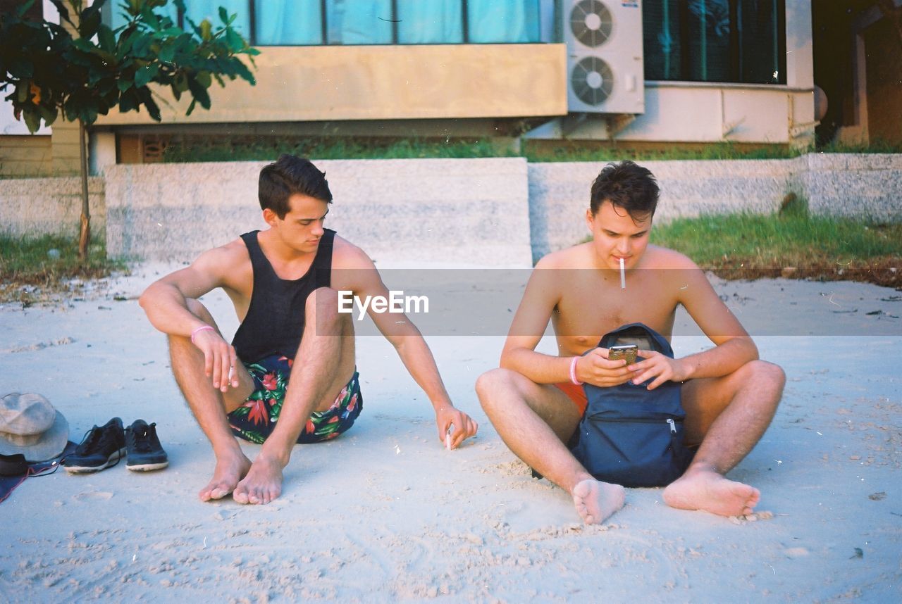 YOUNG MEN SITTING ON BEACH