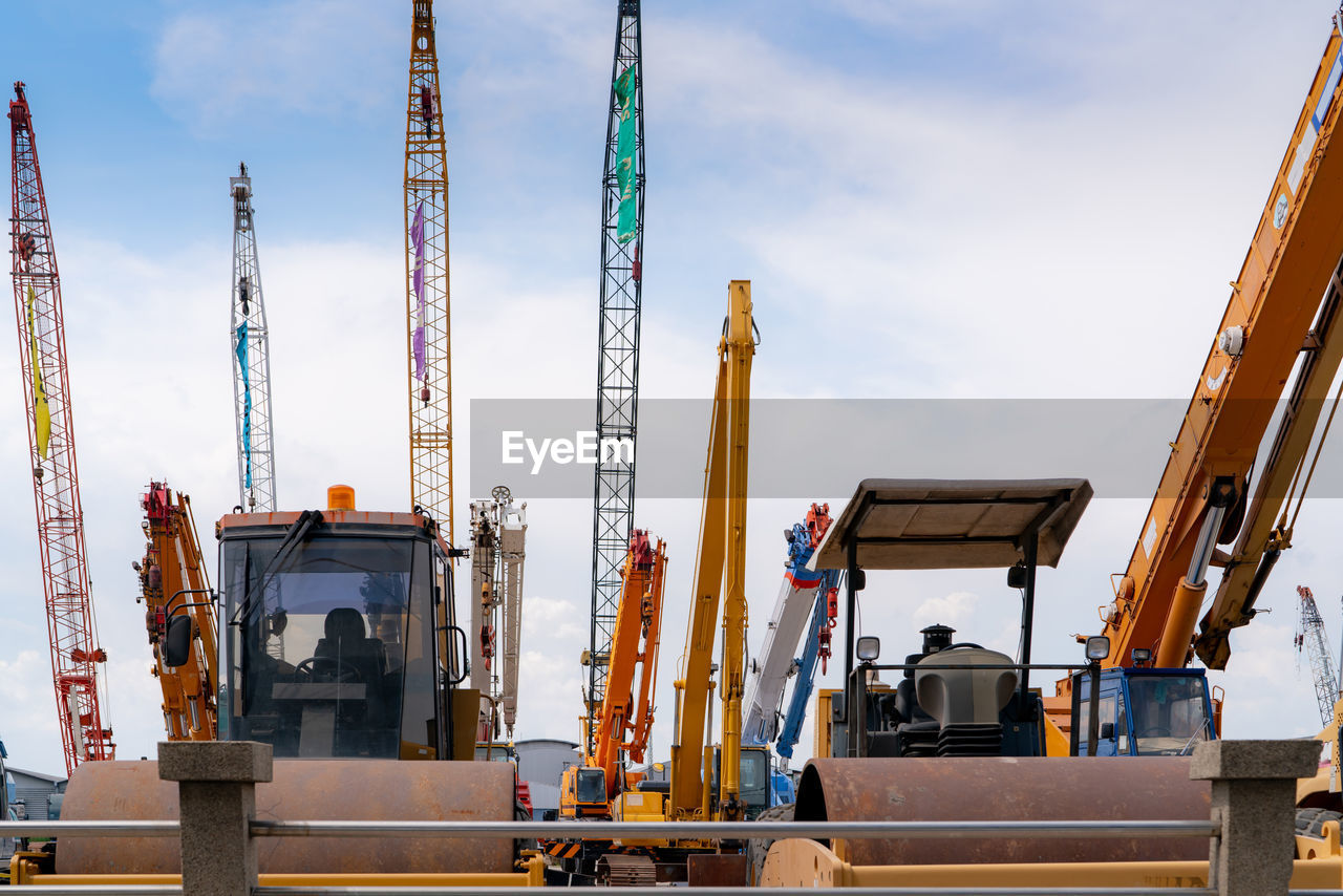 Road roller, mobile crane, and backhoe with long boom. heavy machinery parked at second-hand 