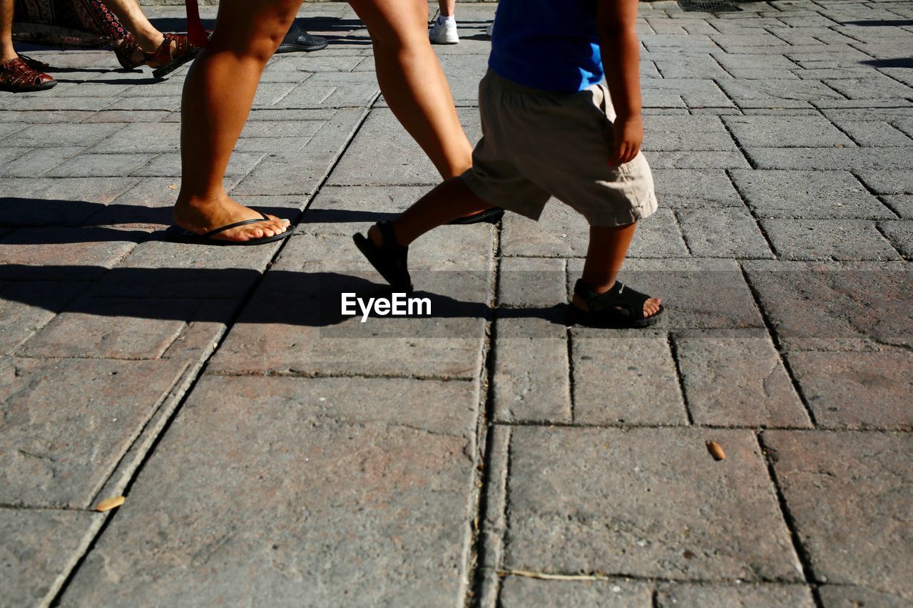 LOW SECTION OF MAN AND WOMAN WALKING ON STREET