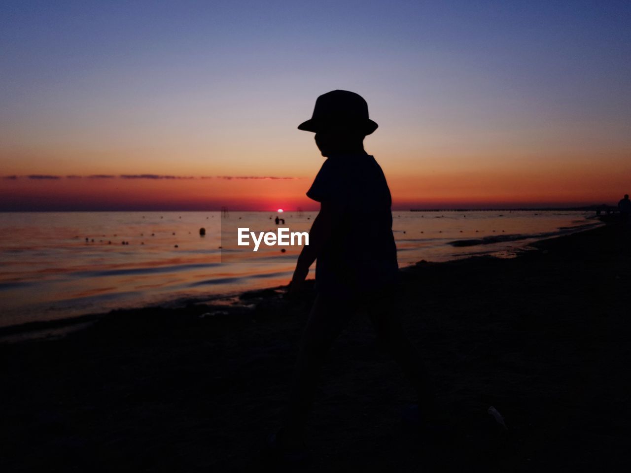 SILHOUETTE MAN STANDING ON BEACH DURING SUNSET