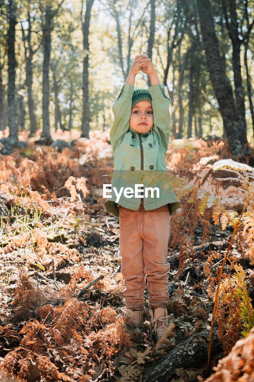 Full length portrait of girl standing against trees in forest