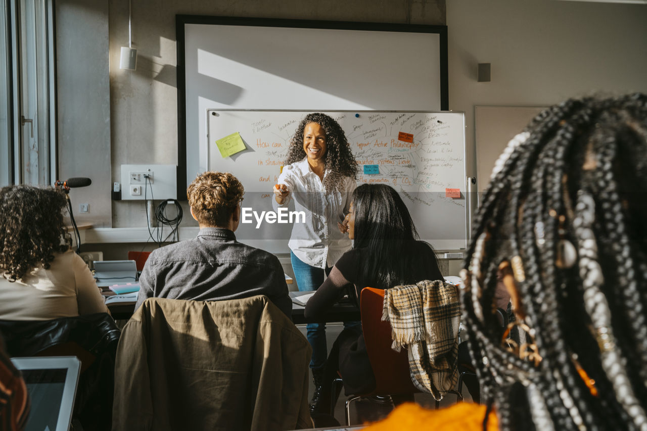 Smiling professor teaching students in classroom at community college