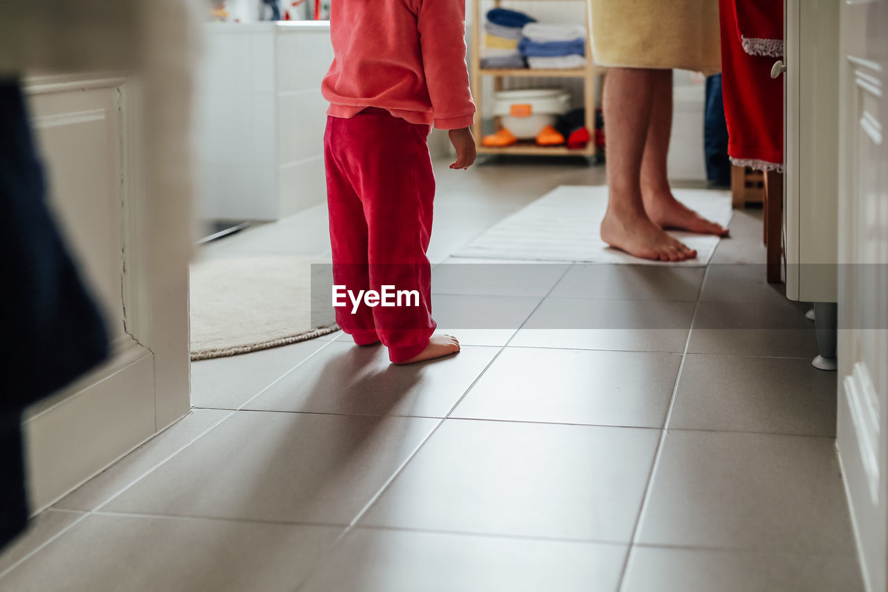 Low section of boy standing with father at home