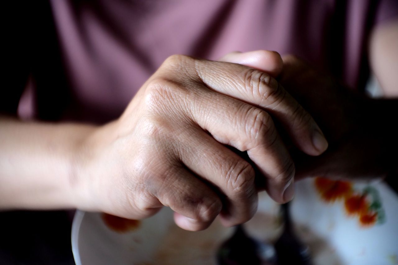 Close-up of hands with food in bowl on table