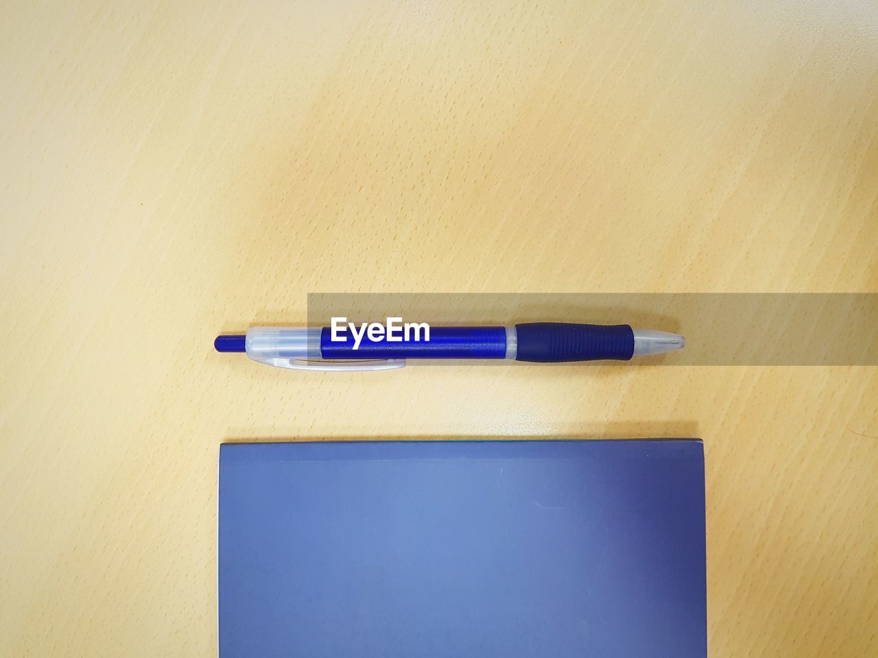 HIGH ANGLE VIEW OF PEN ON TABLE AGAINST BLUE SKY