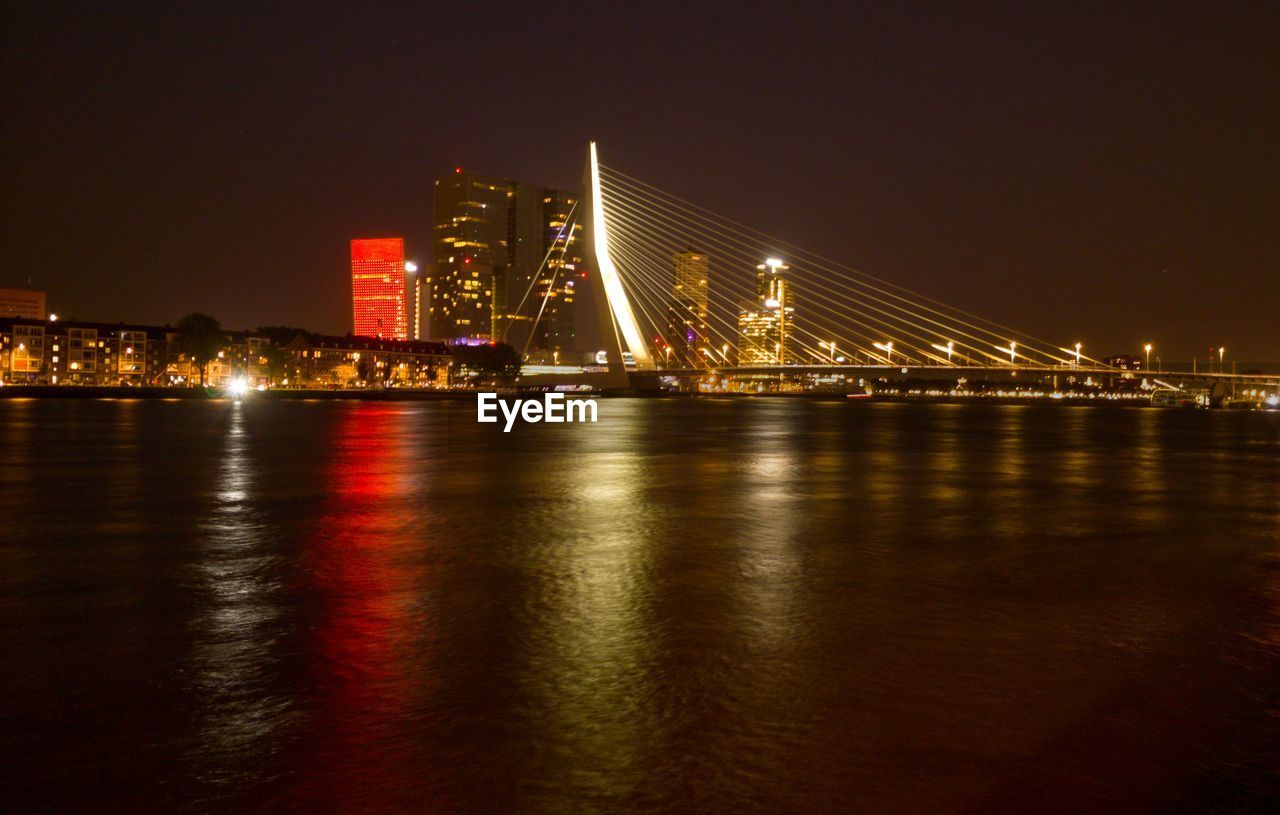 illuminated bridge over river in city at night