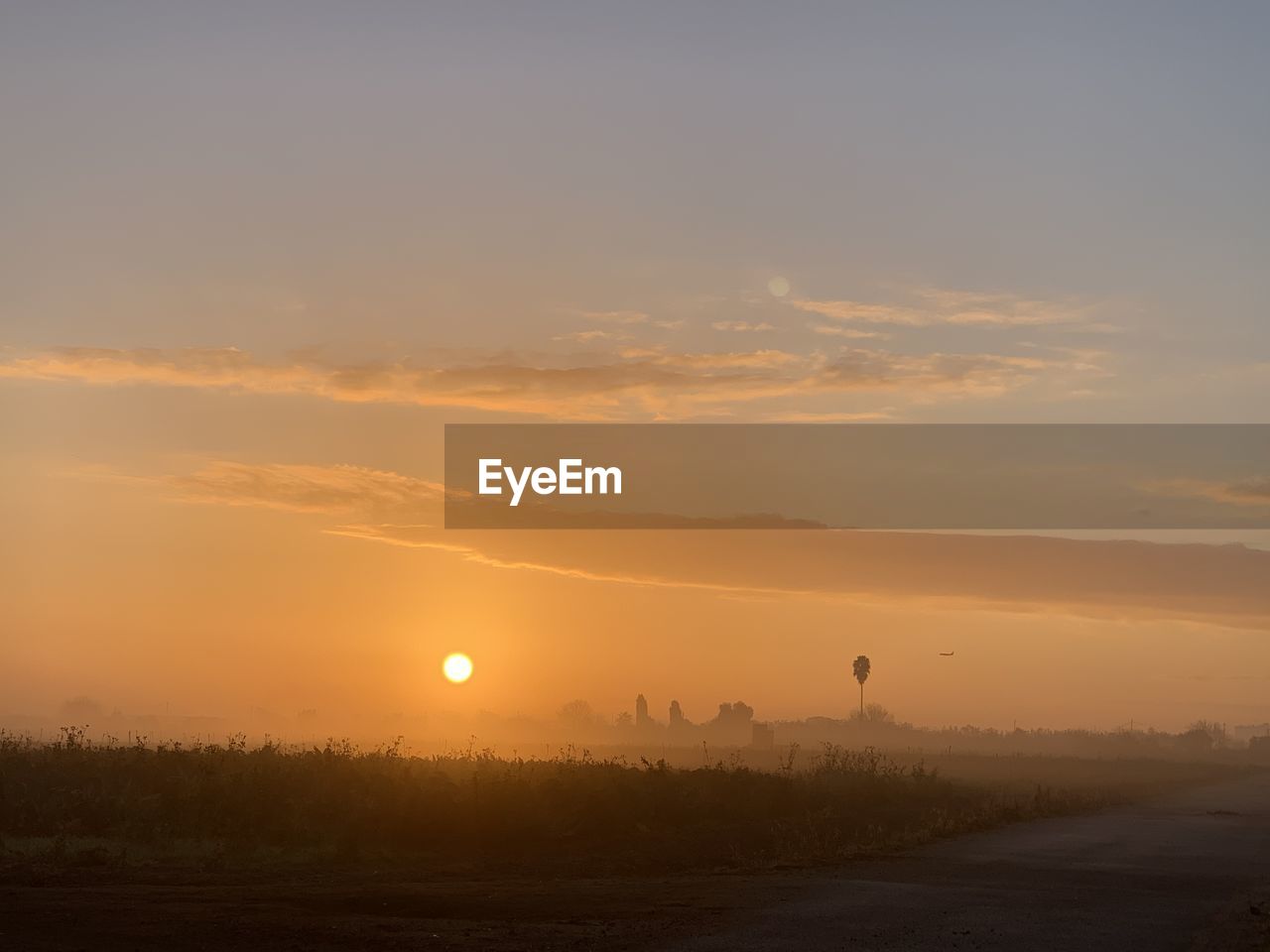 SCENIC VIEW OF SILHOUETTE FIELD AGAINST ORANGE SKY