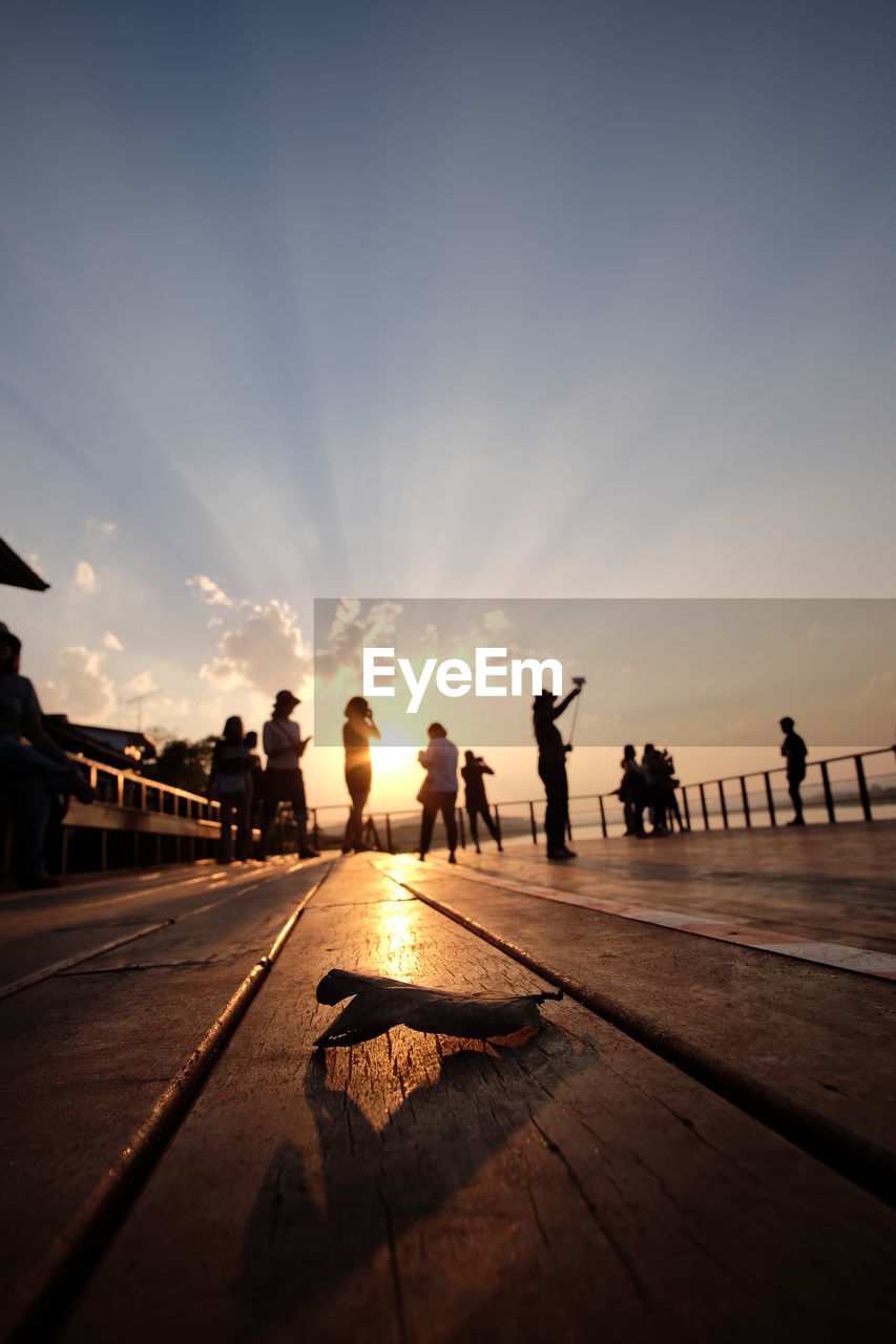 People enjoying the sunset on waterfront footbridge