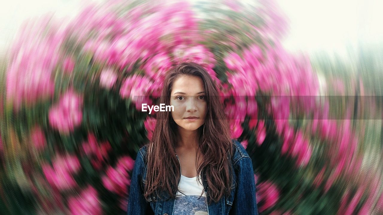 Portrait of beautiful young woman against pink flowering plants