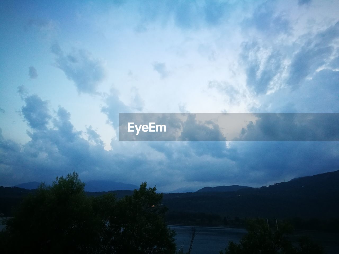 SCENIC VIEW OF LAKE BY SILHOUETTE MOUNTAIN AGAINST SKY