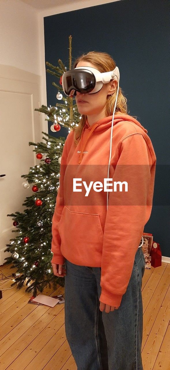 christmas tree, christmas, holiday, one person, celebration, tree, indoors, adult, decoration, clothing, standing, plant, lifestyles, outerwear, three quarter length, person, men, tradition, young adult, home interior, christmas decoration, portrait, emotion, nature, glasses, music