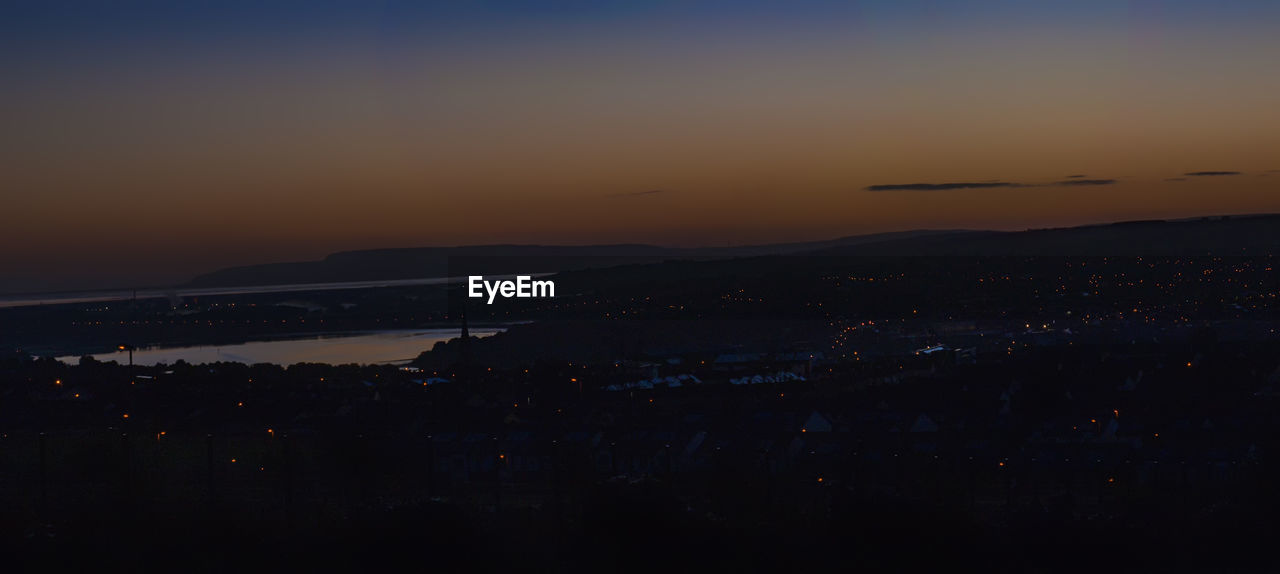 Aerial view of illuminated cityscape against sky at dusk