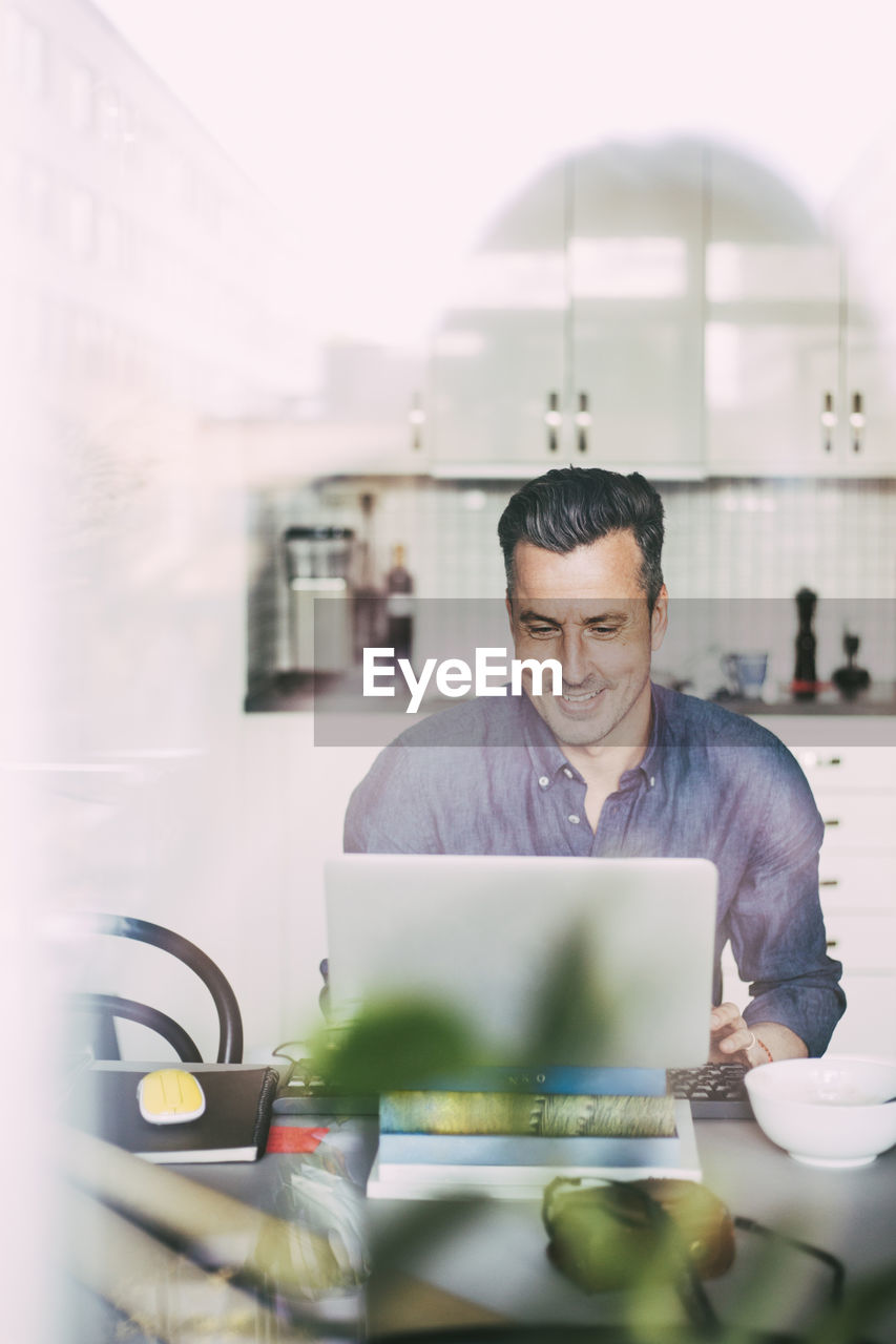 Happy man having video call in kitchen working at home