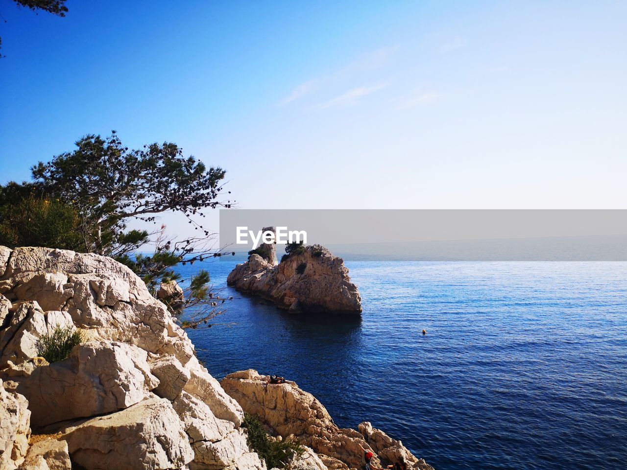 Rocks on sea against blue sky