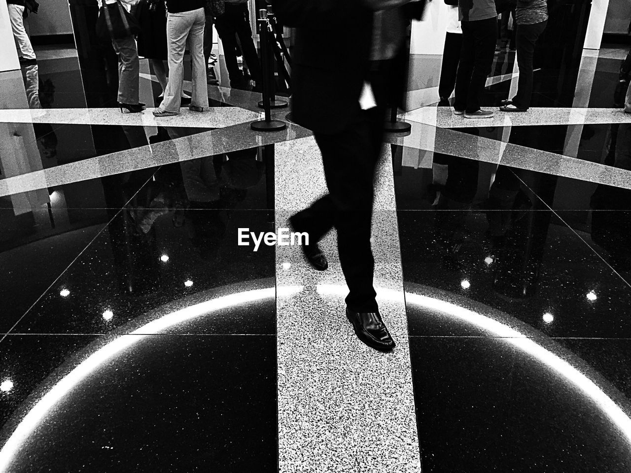 Low section of man walking on illuminated tile floor