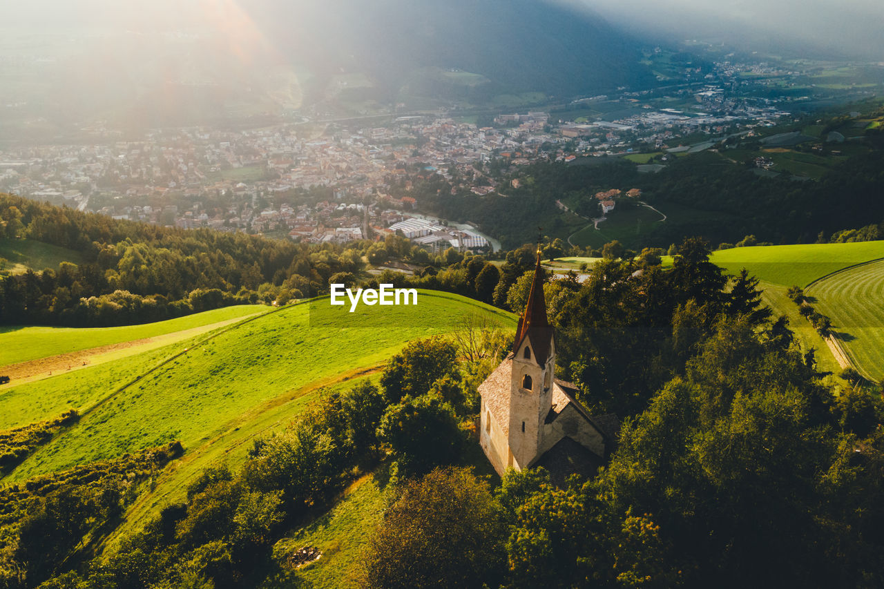 High angle view of a small church with a high steeple on a steep mountain in the alps