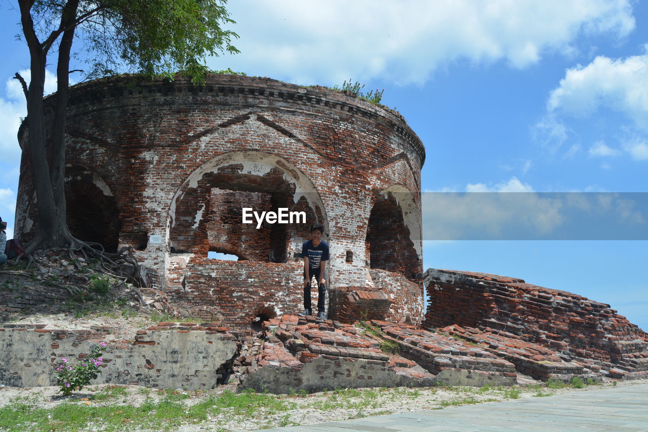 Teenage boy standing against old ruins