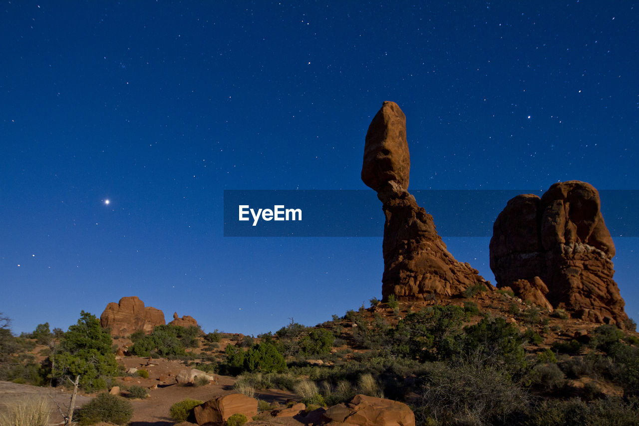 Low angle view of rock formations against blue sky at night