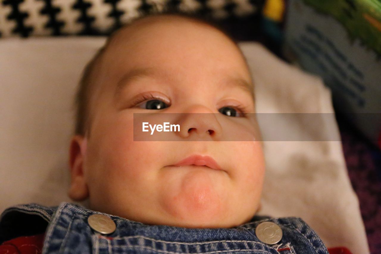 Portrait of cute baby boy lying on bed at home