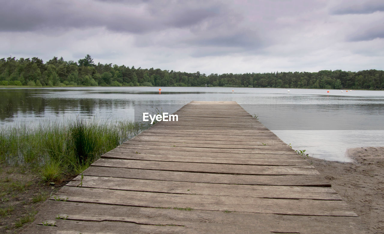 water, sky, cloud, shore, wood, lake, environment, tranquility, nature, landscape, scenics - nature, beauty in nature, land, pier, plant, beach, tranquil scene, tree, jetty, reservoir, overcast, walkway, no people, boardwalk, travel destinations, non-urban scene, the way forward, footpath, holiday, wetland, trip, body of water, summer, outdoors, vacation, forest, travel, architecture, idyllic, day, tourism, rural scene, diminishing perspective, waterway, relaxation, natural environment, water's edge, grass, reflection, social issues, sand, lakeshore, dramatic sky, absence, atmospheric mood, horizon, island, empty, cloudscape, coastline