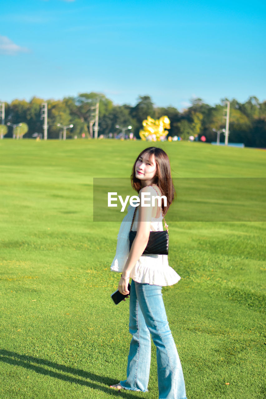 Rear view of woman standing on field against sky