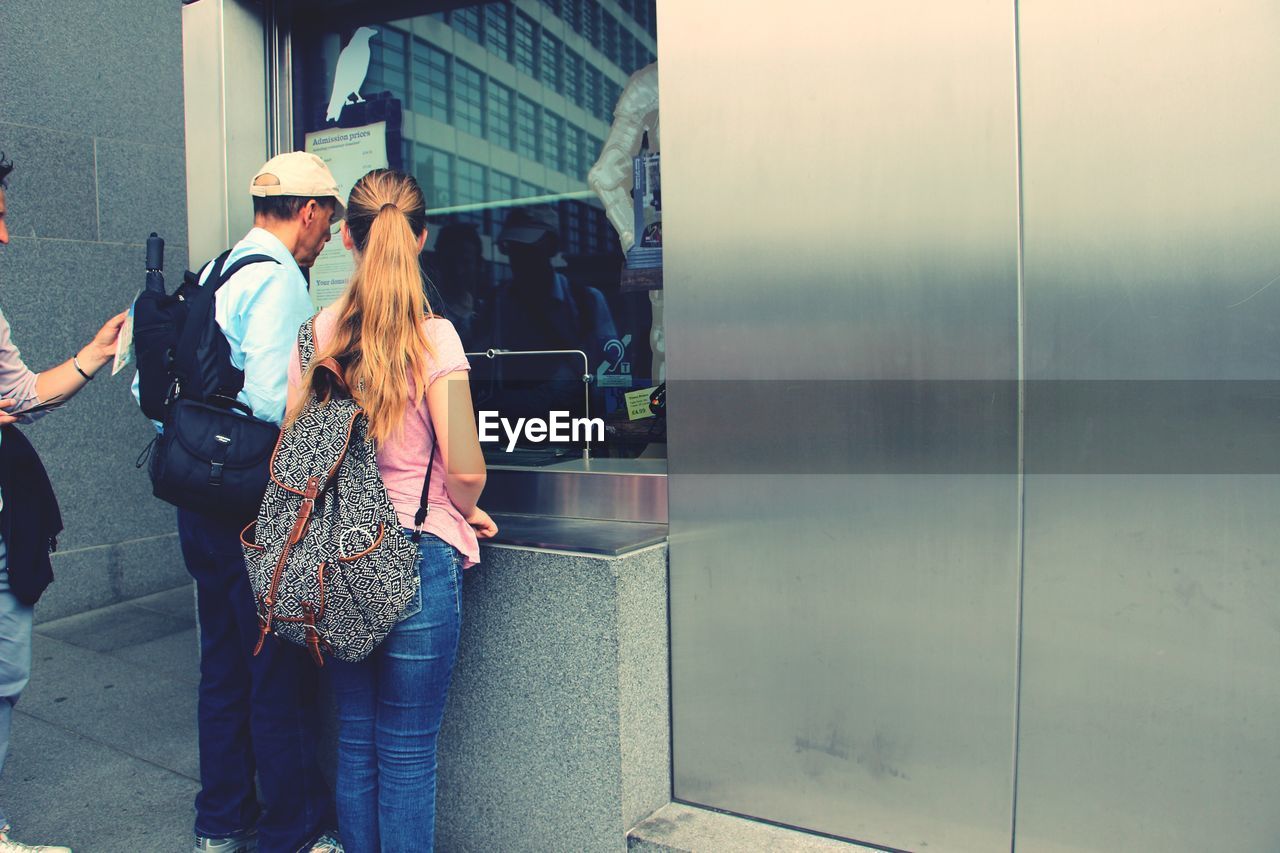 Rear view of people standing at ticket counter