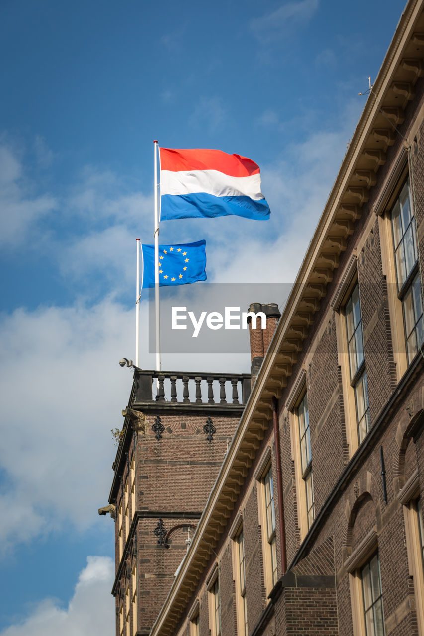 Low angle view of flags on building against sky
