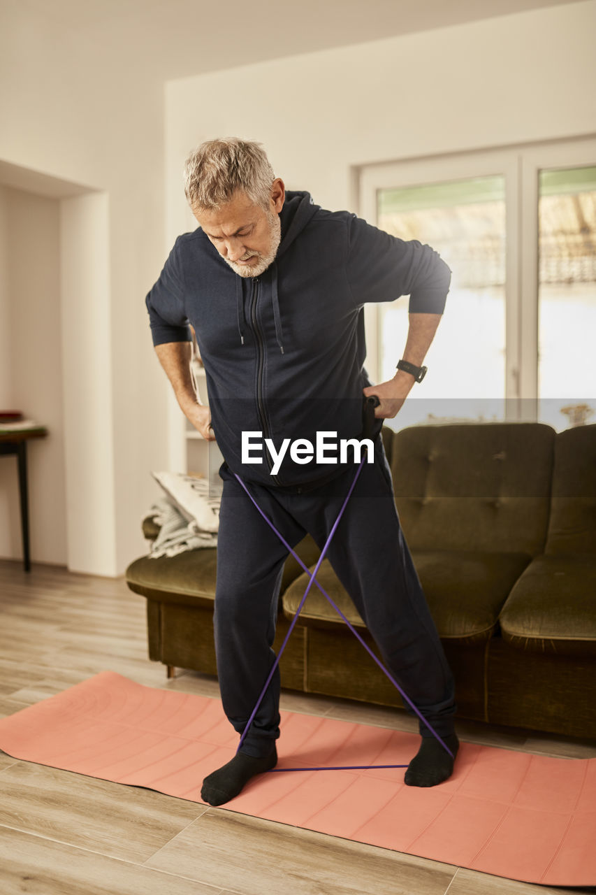Active senior man exercising with resistance band at home